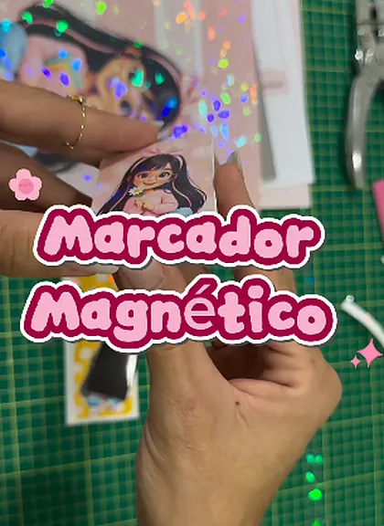 Mãos segurando um marcador de página magnético com estampa holográfica